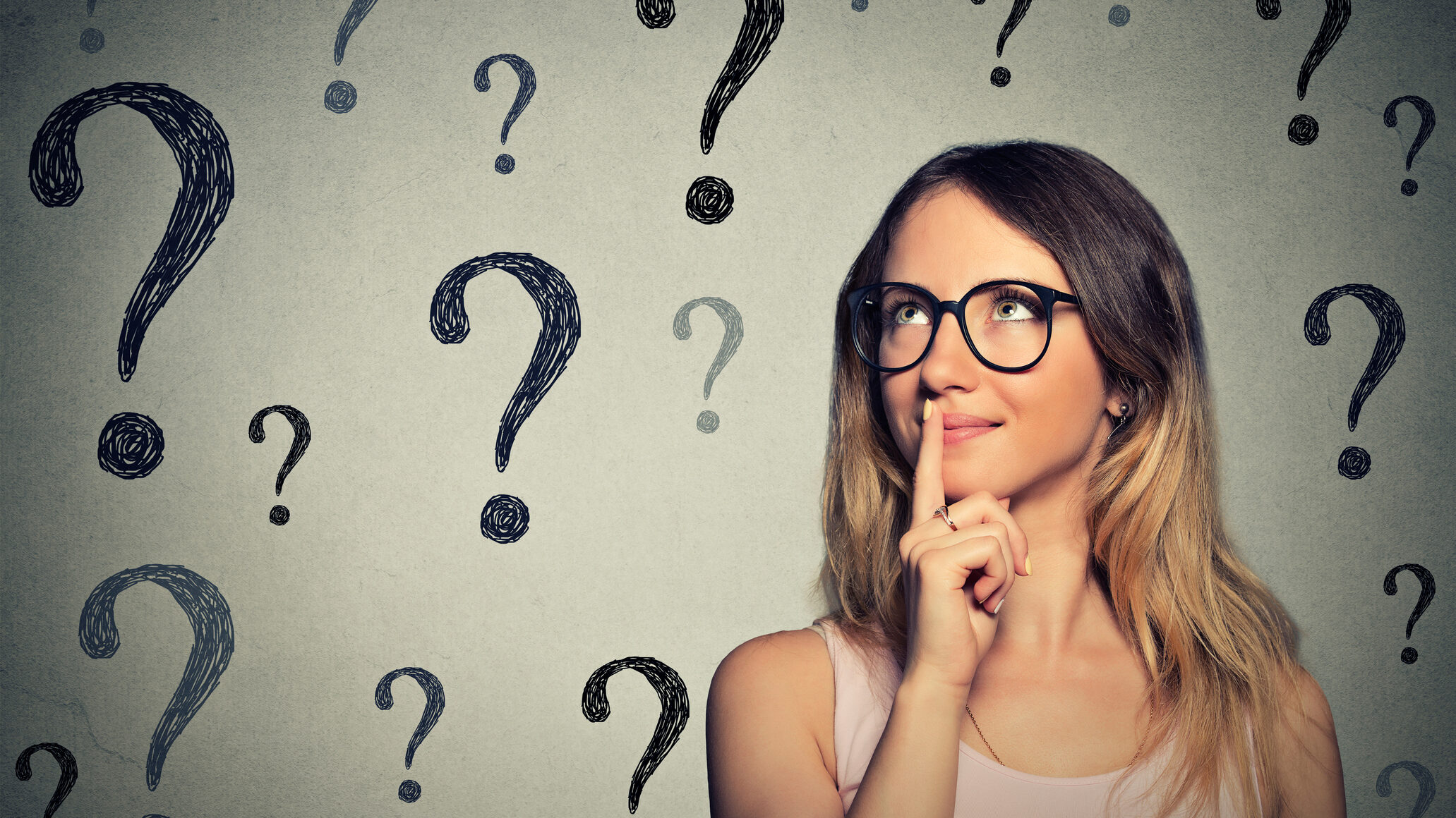 woman with glasses looking up at question marks